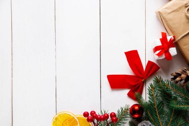 Ahşap beyaz arka planda güzel bir Noel kompozisyonu. Noel hediye kutuları, karlı köknar dalları, kozalaklı kozalaklar, karamel çubuğu, hediye. Yeni yıl. Üst görünüm, alanı kopyala.