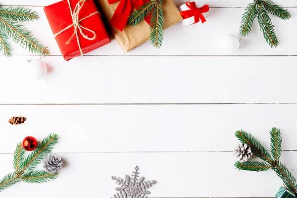 Noel hediyesi kutuları, karlı köknar dalları, kozalaklı kozalaklar, tarçınlı kurutulmuş meyveler, bayram süslemeleri, karamel çubukları olan ahşap beyaz arka planda güzel bir Noel kompozisyonu. Yeni yıl. Üst görünüm, alanı kopyala.
