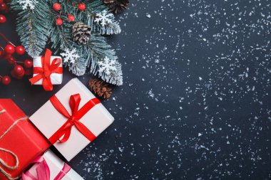 Noel arkaplanı köknar ağacı, Noel hediye kutuları, karlı köknar dalları, kozalaklı kozalaklar, koyu arkaplanda hediye. Üst Manzara. Uzayı kopyala Yeni yıl. Dekorasyon