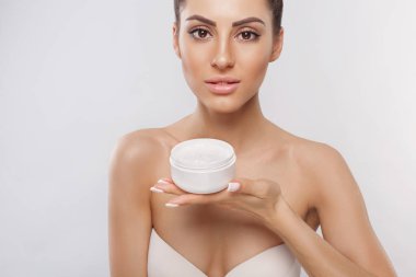 Güzellik Konsepti. Kadın elinde nemlendirici kozmetik krem tutuyor. Cilt bakımı. Yumuşak ten ve çıplak omuzlar.