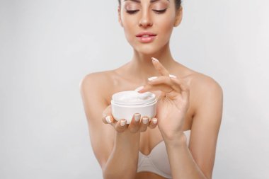 Yaklaşık yüz kremi uygulamak için bir kadının elleri. Moisturizing Lotion.Close-up genç tutan uygulama kızın güzel yüz nemlendirici krem