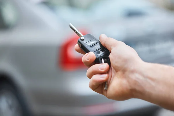 Närbild Hand Man Håller Bil Nyckel Med Suddig Bil Bakgrunden — Stockfoto