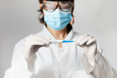 Doktor termometreye bakıyor. Dijital termometreyi tutan kadın eller. Kız sıcaklığı ölçer. Vücut sıcaklığını virüs belirtileri için kontrol edin. Grip, salgın koronavirüs.
