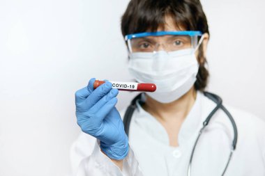 Koruyucu eldivenler, maske ve gözlük takan doktor 2019 nCoV analizi için kan tüpü tutuyor. Kan örneği. Corona virüsü salgını. Salgın Virüsü Solunum Sendromu.
