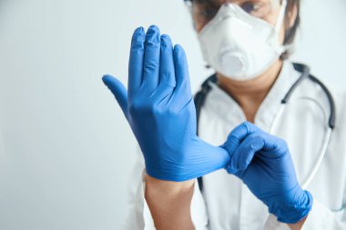 Tıp doktoru muayeneden önce koruyucu eldiven takıyor. Koronovirüse karşı koruma