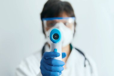 Koruyucu maske takan doktor vücut ısısını kontrol etmek için kızılötesi alın termometresi kullanmaya hazır. Salgın virüs salgını konsepti. Coronavirüs. Termometre tabancası.