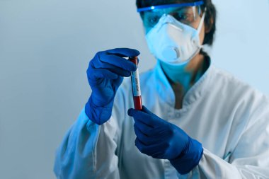 Coronavirus 2019 nCoV kan örneği. Koruyucu eldivenli, maskeli ve gözlüklü bir doktor 2019 nCoV analizi için üzerinde kan olan test tüpü tutuyor. Coronavirus kan testi konsepti. Aşı araştırması