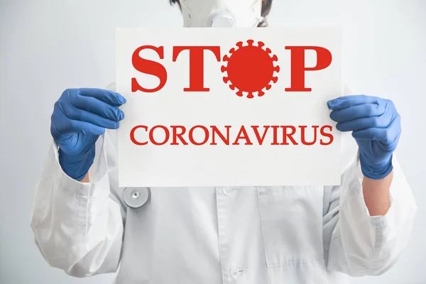 Doctor in a medical mask shows the tablet with the words STOP VIRUS. Coronavirus epidemic protection. Coronavirus quarantine and Air pollution. Wuhan, China epidemic virus symptoms background, copy space