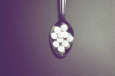 kaşık beyaz yuvarlak hapları yığını.