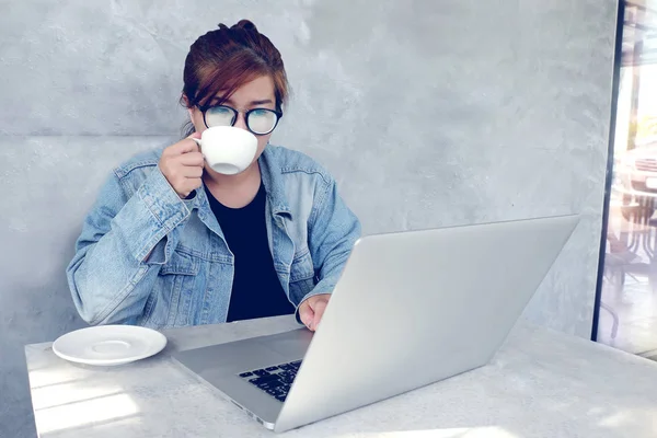 Молодая женщина работает на ноутбуке и пить кофе в кафе — стоковое фото