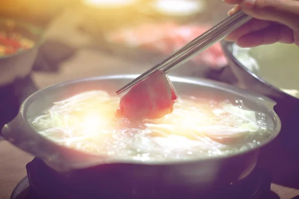 Olla caliente shabu shabu, mano sosteniendo palillos con carne hervida en — Foto de Stock