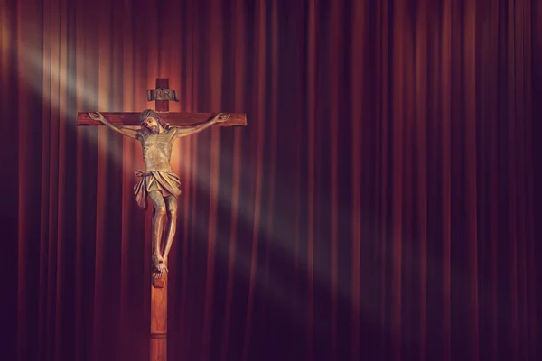 Crucifix, Jésus sur la croix dans l'église avec rayon de lumière sur fond de rideau rouge — Photo