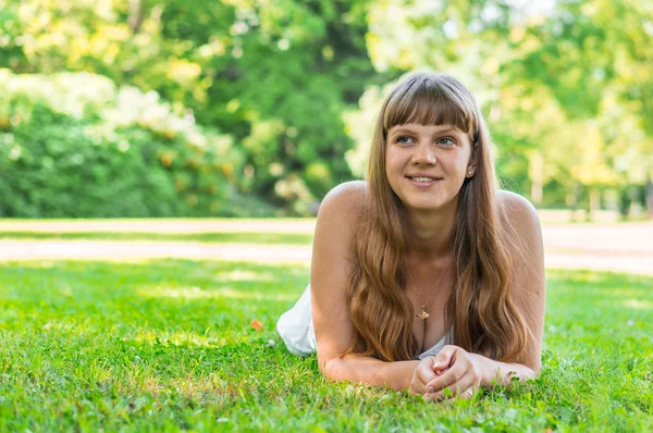 Joven hermosa mujer en vestido blanco acostado en la hierba — Foto de Stock