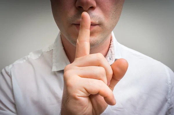 Sessizlik jest yapma dudaklarında parmak ile çekici bir adam — Stok fotoğraf