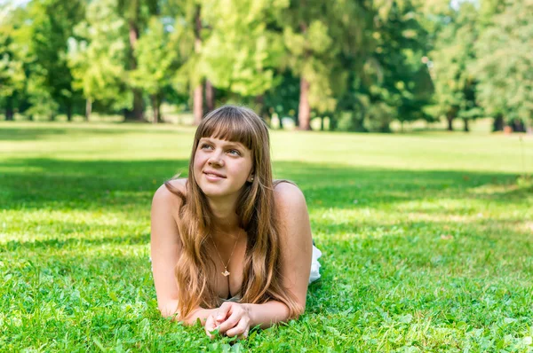 Junge hübsche Frau liegt auf dem Gras — Stockfoto