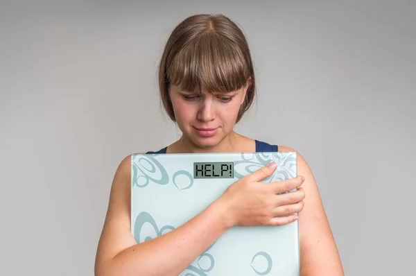 Frustrated overweight woman holding digital scales with HELP!