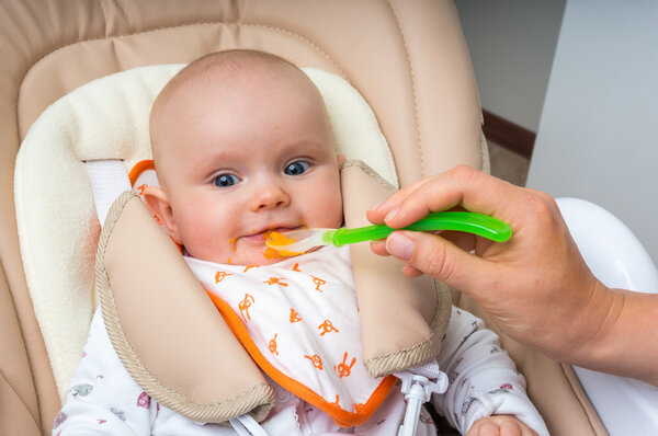 Mother feeding her baby girl with a spoon