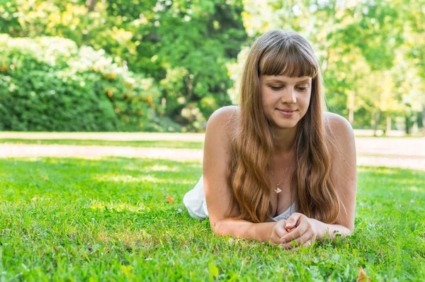 Joven hermosa mujer en vestido blanco acostado en la hierba — Foto de Stock