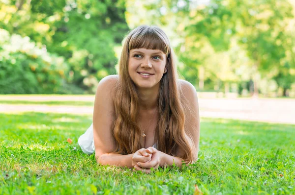 Joven hermosa mujer en vestido blanco acostado en la hierba — Foto de Stock