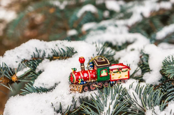 Red Christmas toy train on snowy branch fir — Stock Photo, Image
