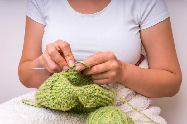 Mãos de mulher com agulhas de tricô com lã verde — Fotografia de Stock