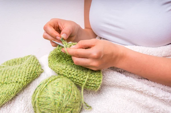 Mãos femininas com agulhas de tricô com lã verde — Fotografia de Stock