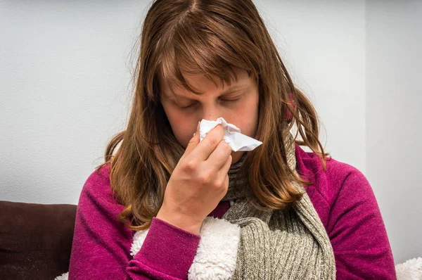 Sick woman having flu and sneezing into handkerchief
