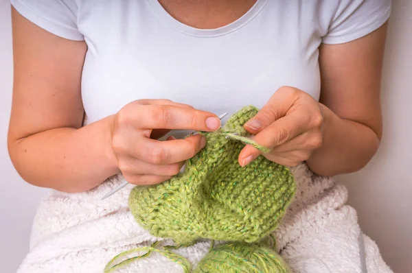 Mãos femininas com agulhas de tricô com lã verde — Fotografia de Stock