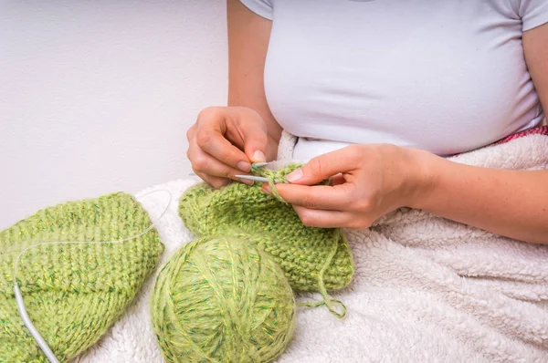 Mãos de mulher com agulhas de tricô com lã verde — Fotografia de Stock