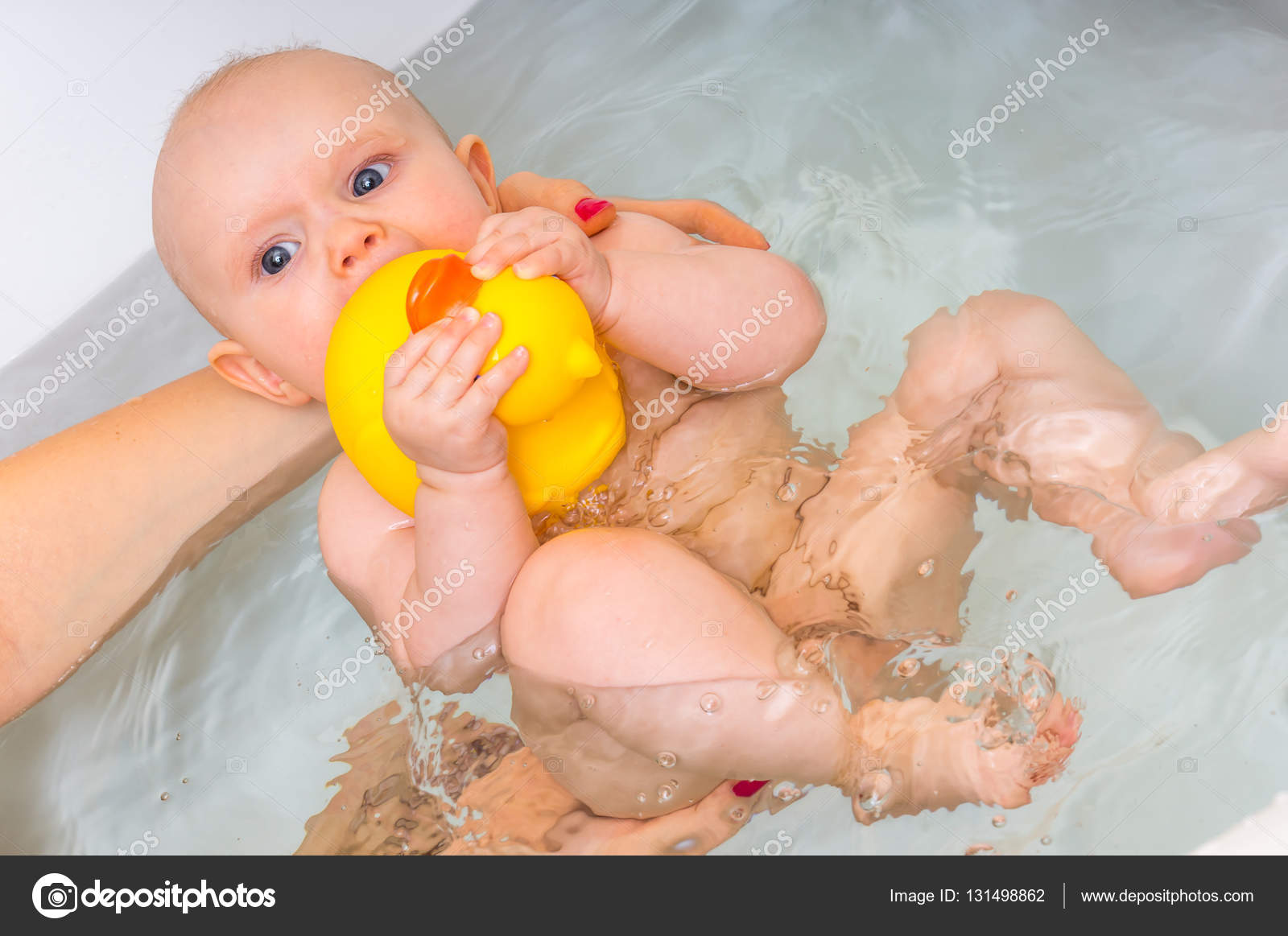 Newborn baby girl bathing and playing with rubber duck Stock Photo