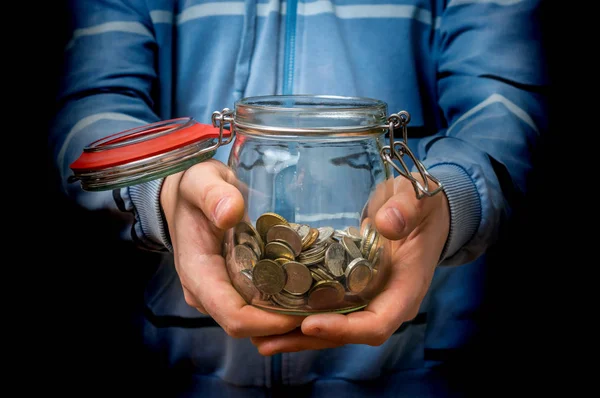 Homme en sweat-shirt bleu tenant pot d'argent avec des pièces — Photo