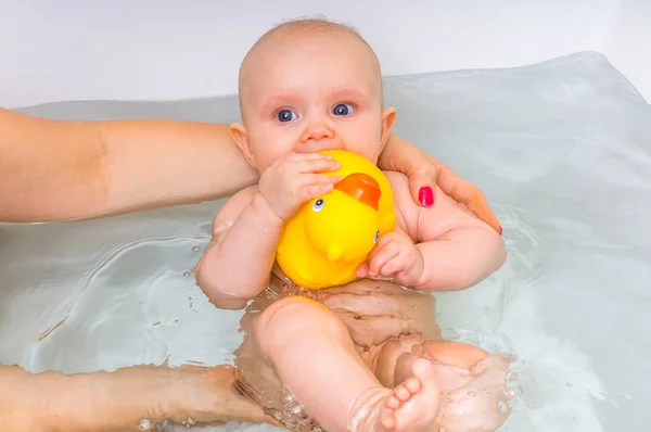 Новорожденная девочка купается и играет с резиновой уткой — стоковое фото