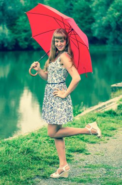 Gölet yakınındaki kırmızı şemsiye ile genç bayan