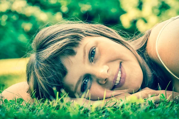 Young beautiful teenage girl lying on the green grass — Stock Photo, Image