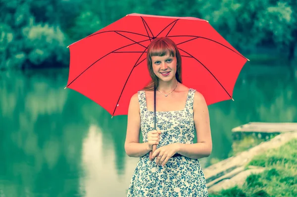 Junge Dame mit rotem Regenschirm in Teichnähe — Stockfoto