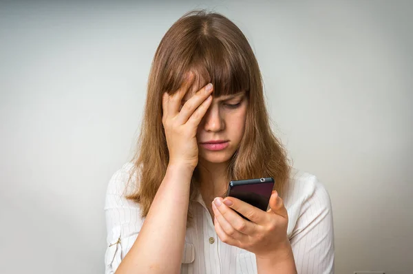 Mujer decepcionada sosteniendo y mirando en el teléfono móvil — Foto de Stock