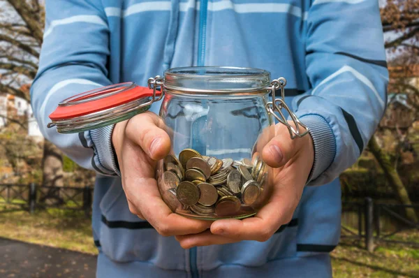 Homme en sweat-shirt bleu tenant pot d'argent avec des pièces — Photo