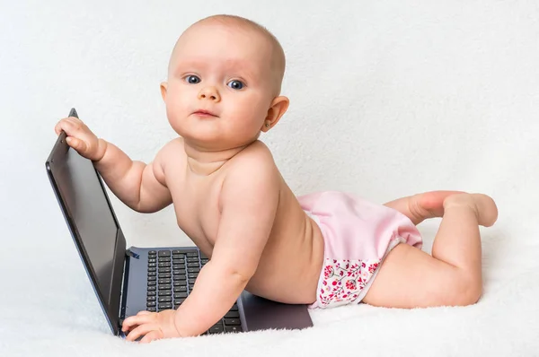 Cute baby girl in a diaper playing with laptop