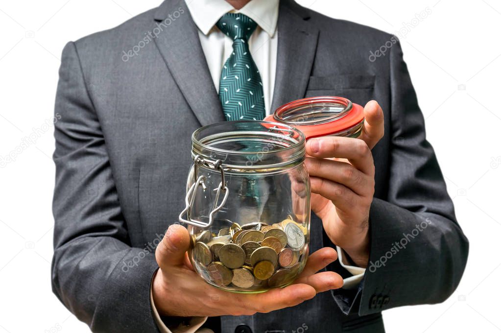 Businessman in black suit holding money jar with coins