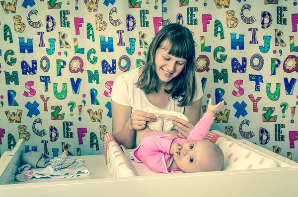 Mother changing diaper to her little baby in child room — Stock Photo, Image