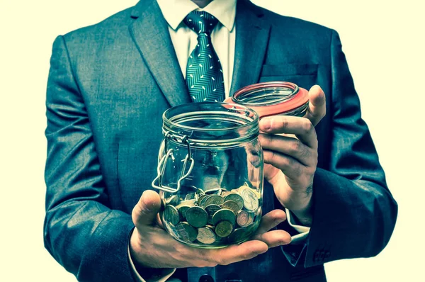 Man in black suit holding money jar with coins - retro style — Stock Photo, Image