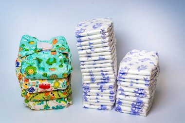 Compare reusable cloth diapers with pile of disposable diapers clipart