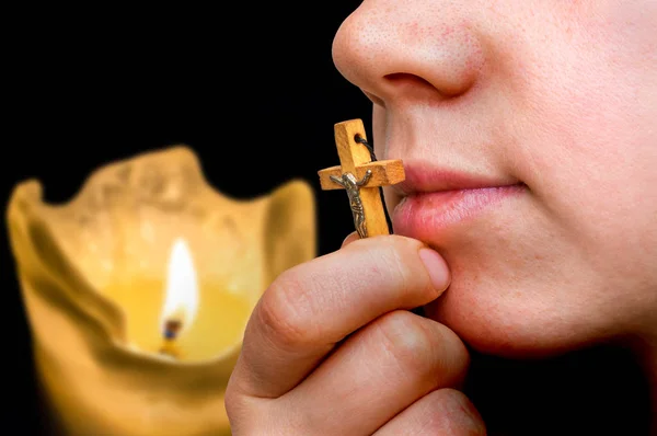 Female hand with wooden cross on candles background