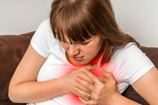 Mujer en sofá teniendo un ataque al corazón —  Fotos de Stock