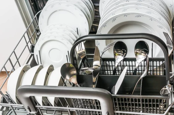 Open dishwasher with clean dishes after cleaning process