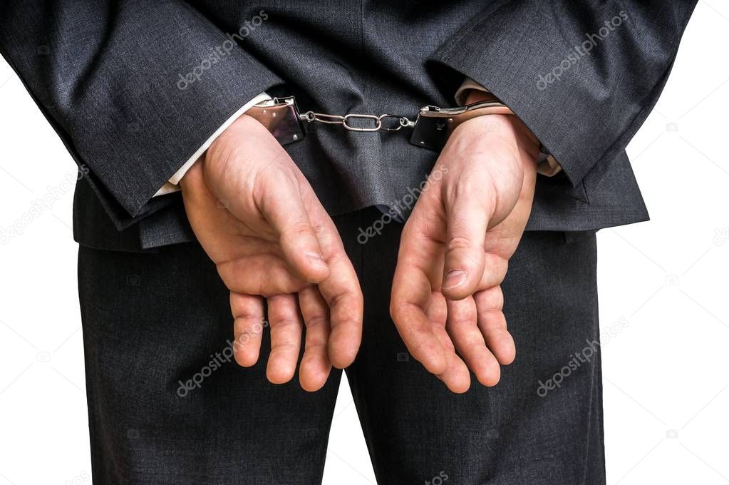 Arrested businessman in handcuffs with hands behind back