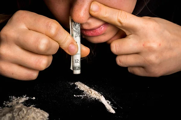 Джинсова жінка хропить кокаїновий порошок з рулонною банкнотою — стокове фото