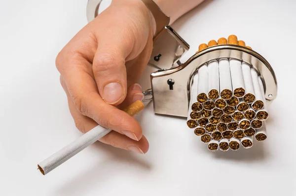 Female hand with handcuffs and cigarettes on white — Stock Photo, Image