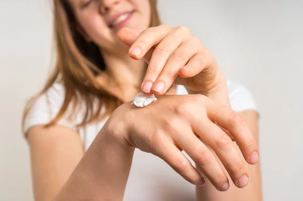 Souriant jeune femme appliquant de la crème sur ses mains — Photo