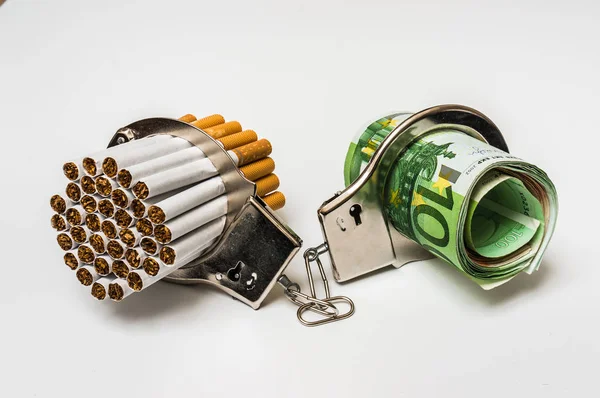 Сигареты и деньги с наручниками - стоимость курения — стоковое фото
